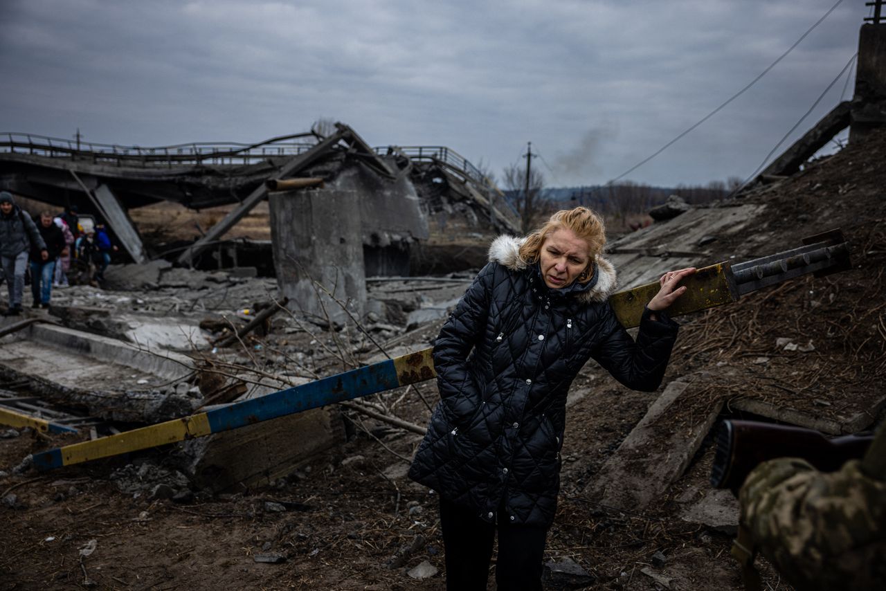 An evacuee of Irpin crosses a destroyed bridge 