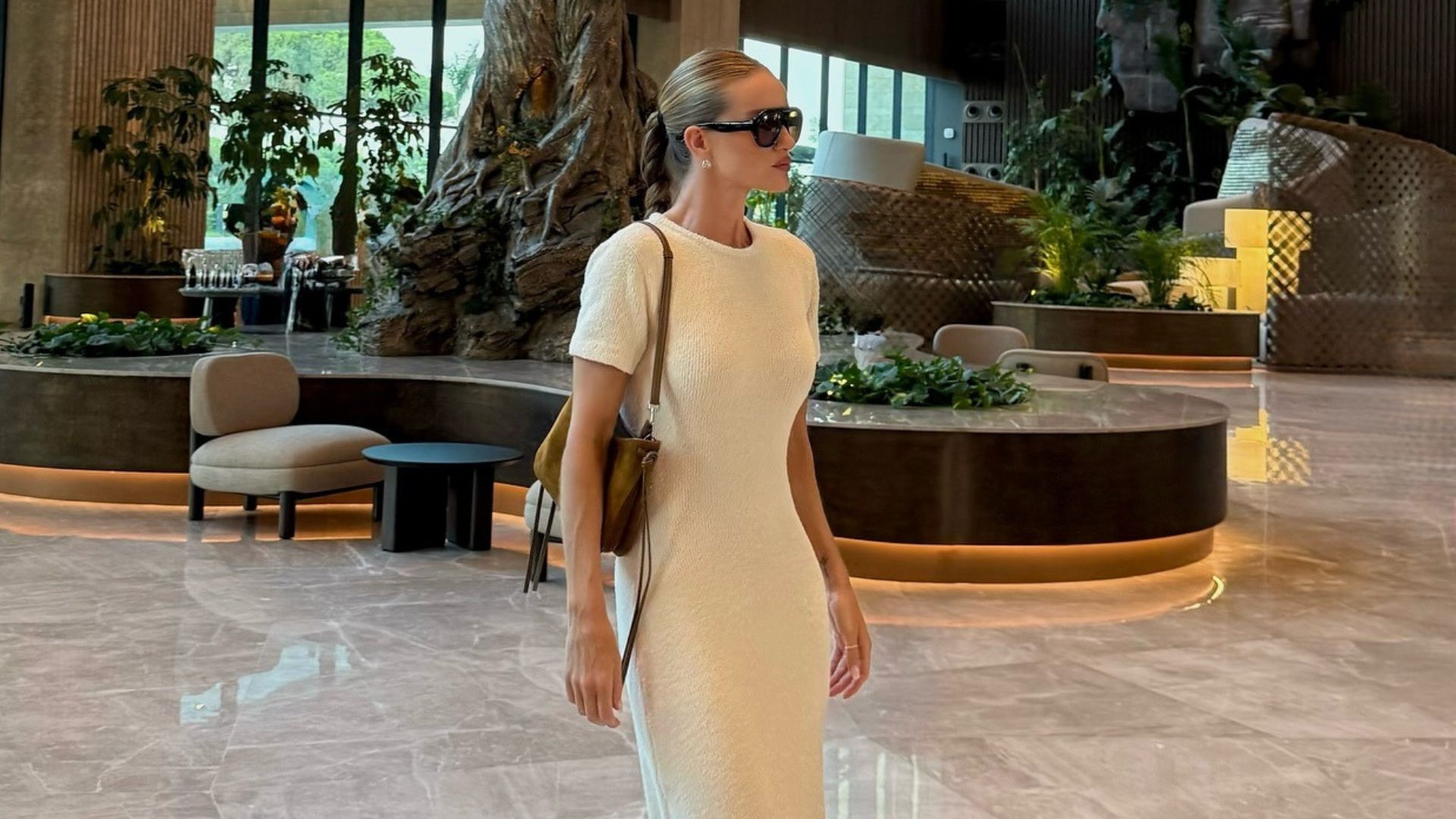 Rosie Huntington-Whiteley wears a longline boucle t-shirt dress with a light khaki suede handbag, flip-flops and dark sunglasses.