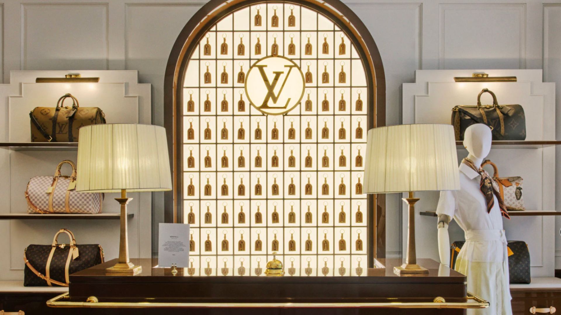an image of the lobby at the Louis Vuitton hotel, showing a check in desk with a wall of branded luggage tags behind it