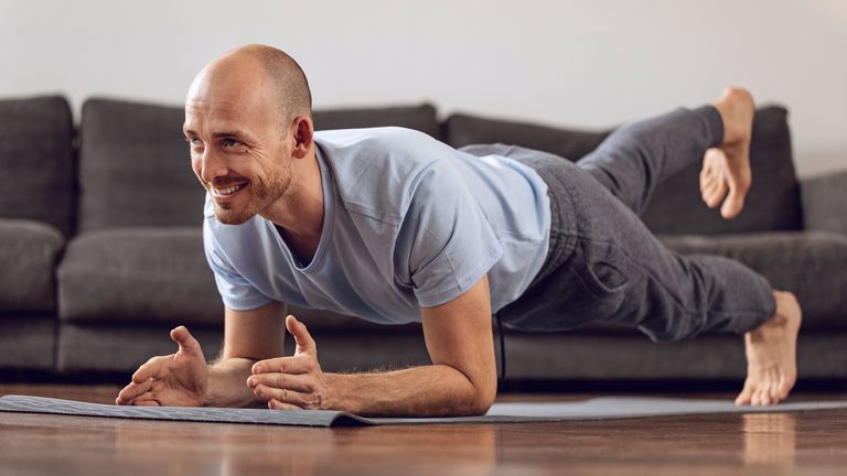 Man workouts in his living room using bodyweight exercise