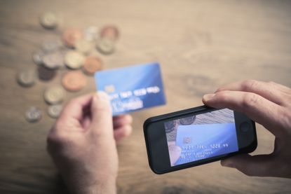 Mans hands photographing credit card using smartphone