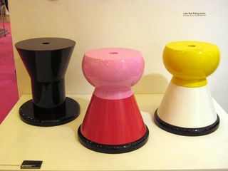Three colourful ceramic stools displayed on a white platform