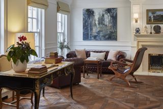 parquet flooring in traditional living room with leather sofa armchair and desk
