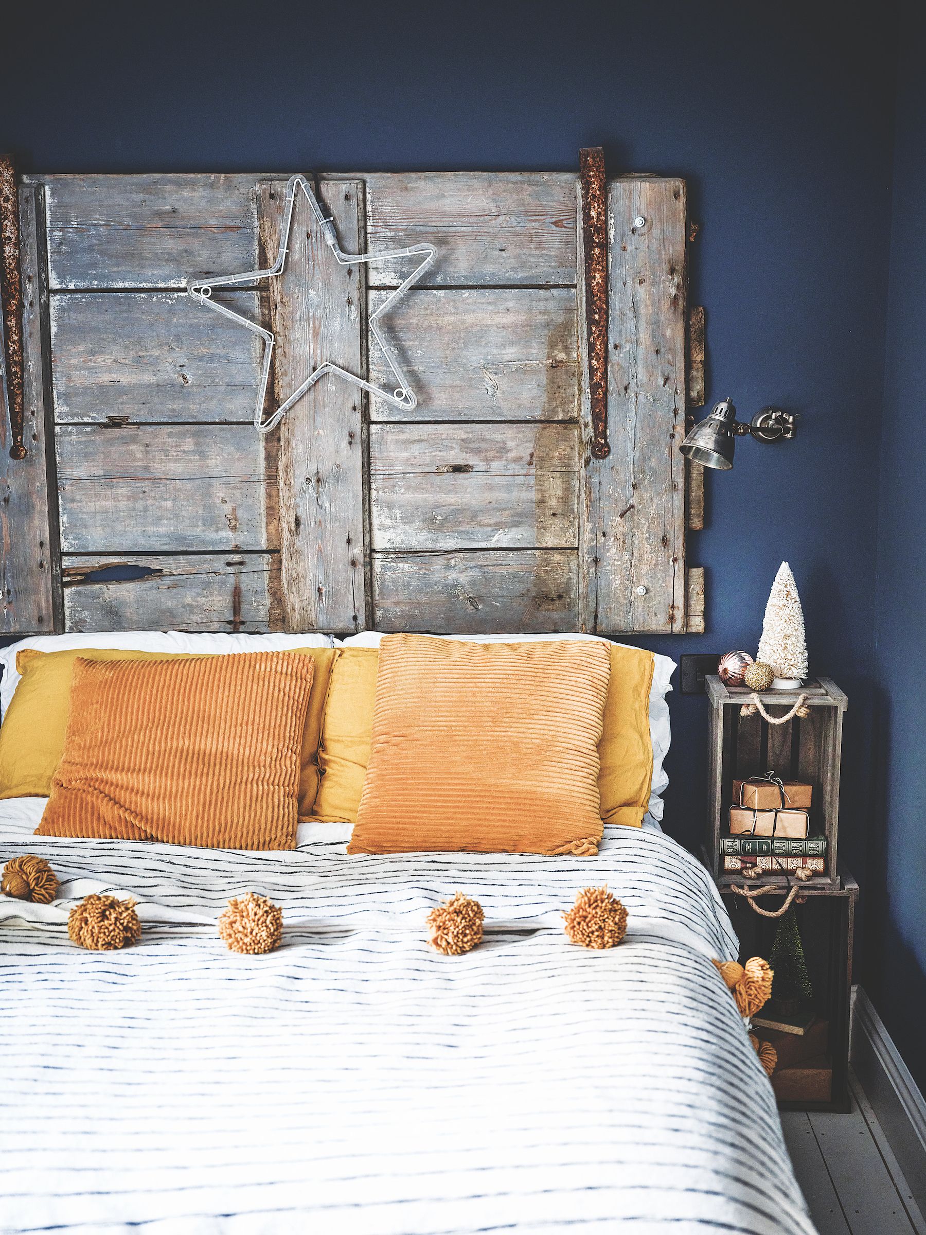 bedroom with antique rustic door used as headboard and russet cushions