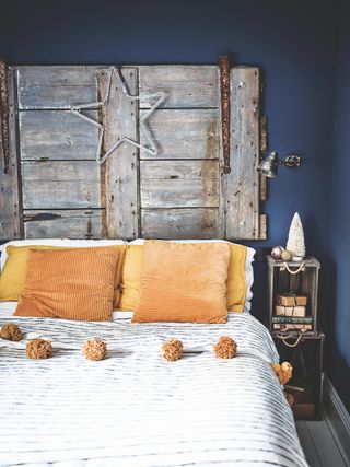 bedroom with antique rustic door used as headboard and russet cushions