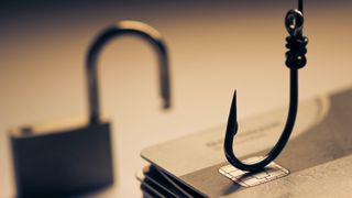 A fishing hook rests on top of a stack of credit cards, while a padlock sits in the background out of focus