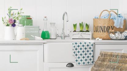 White kitchen with butler sink with countertop filled with laundry baskets and products and spring bulbs and flowers