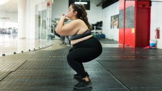 Woman in gym doing bodyweight squats