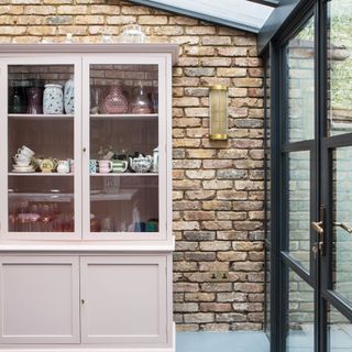 Brick wall with glass aluminum door and blush wall cabinet