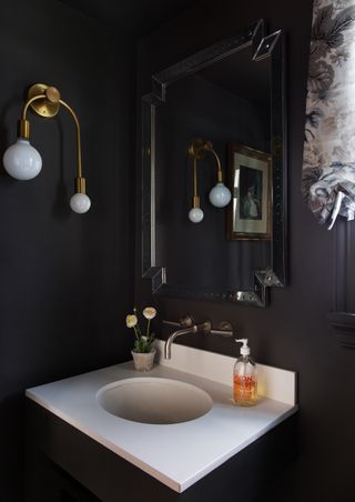 A black bathroom with wall black walls and gold fixtures