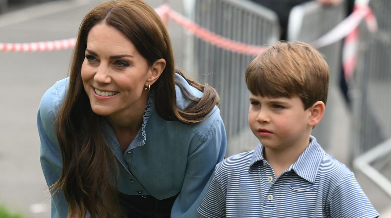 Princess Kate wears a blue shirt and stands with son Prince Louis, who is wearing a blue and white checked shirt