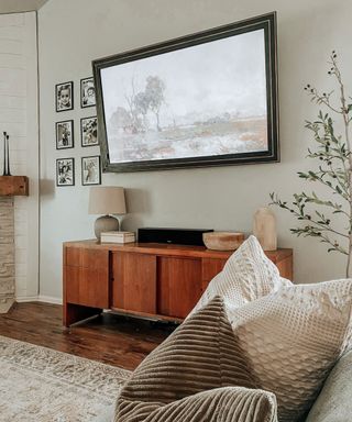 living room with a DIY frame tv, wooden TV unit and family photos