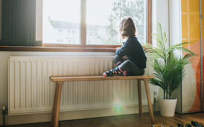 Boy sitting on bench at home looking out of the window