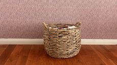Wicker laundry basket against pink plaid wallpaper