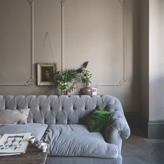 how to decorate a north-facing room, living room with stone walls, architectural detailing, herringbone floor, grey button backed sofa, artwork, plants, coffee table