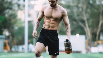 man with a six-pack walking holding a water bottle