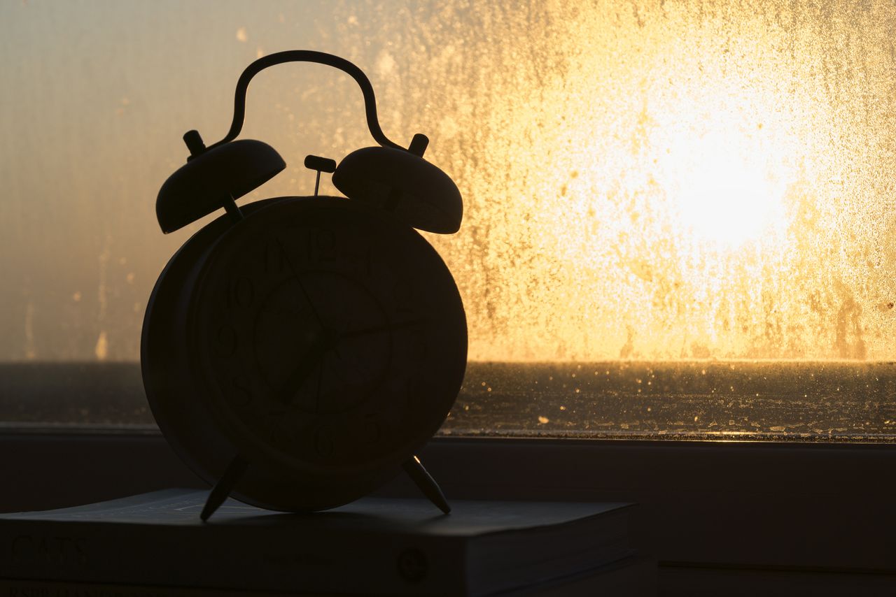 The sun rising over an alarm clock. 