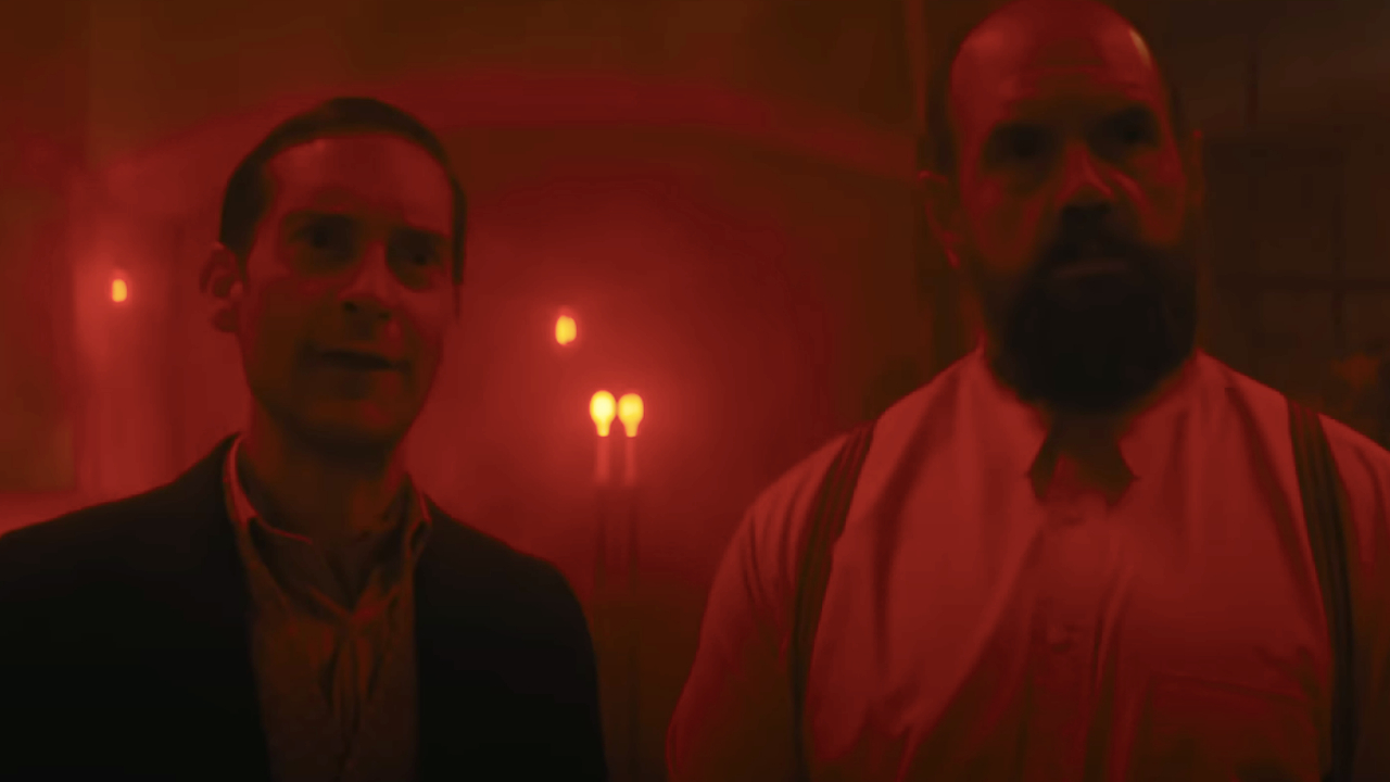 Tobey Maguire and Ethan Suplee in a dungeon bathed in red light in Babylon.