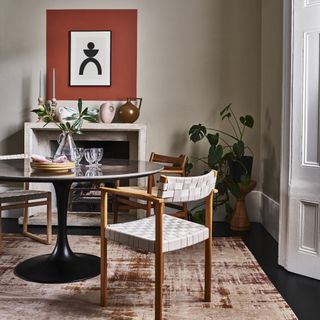 A dining area with a round dining table and a concrete modern fireplace with an artwork hung above it