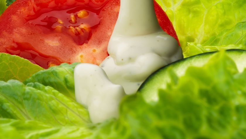 A closeup of ranch dressing pouring onto a salad