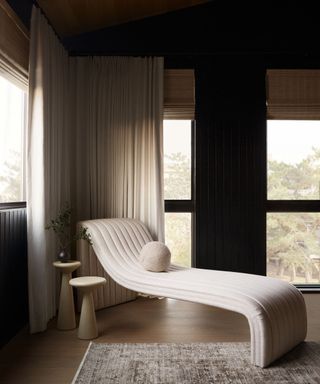 A seating corner in a bedroom with large windows and a sculptural white lounge chair