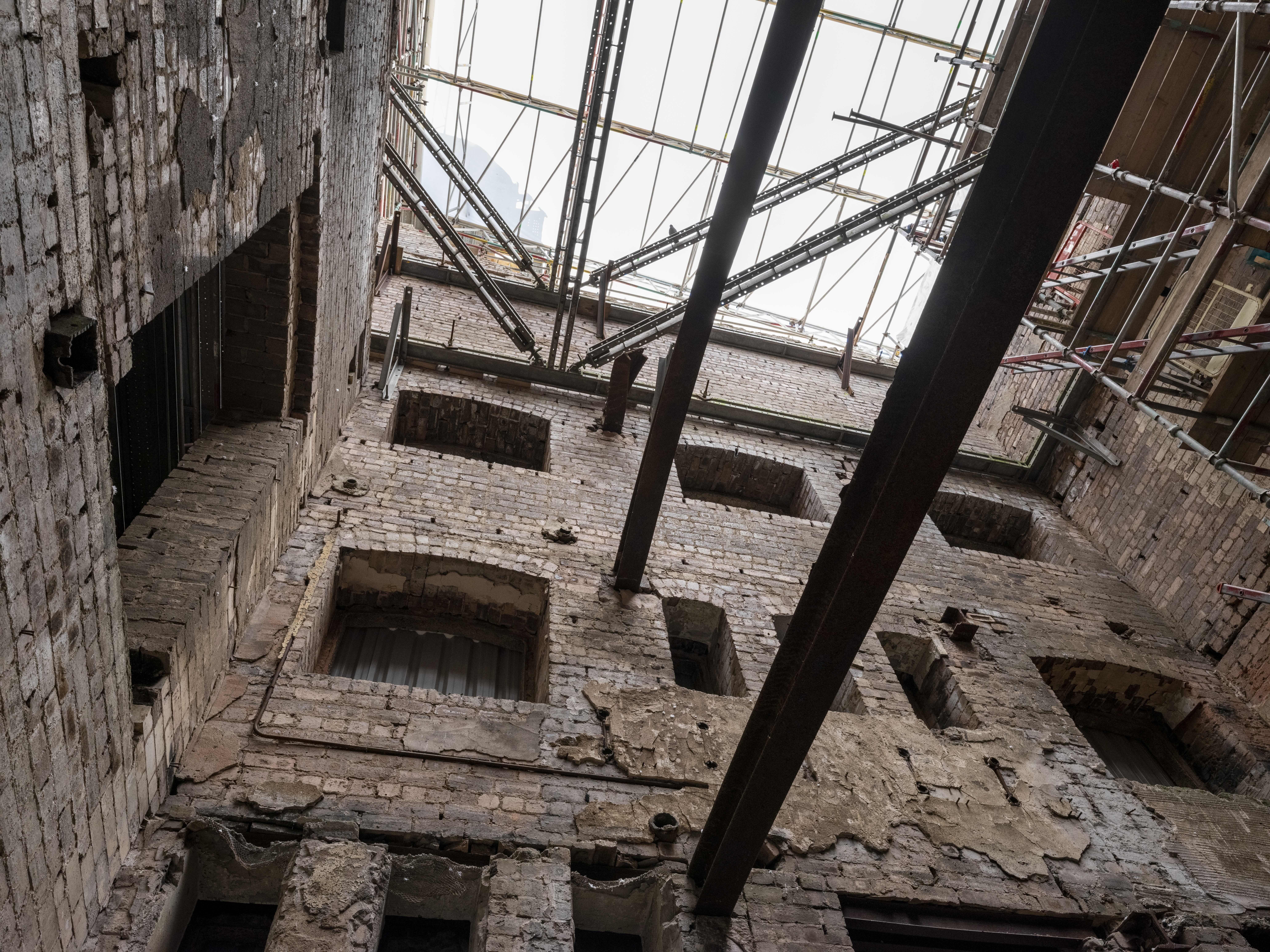 A view of the burnt out interior of the building, with exposed bricks covered in scaffolding.