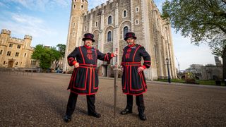 Two Beefeaters hold a Final Fantasy sword outside the Tower of London.