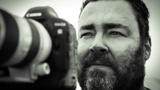Monochrome image of filmmaker Matt Norman with his Canon EOS-1DX Mark II
