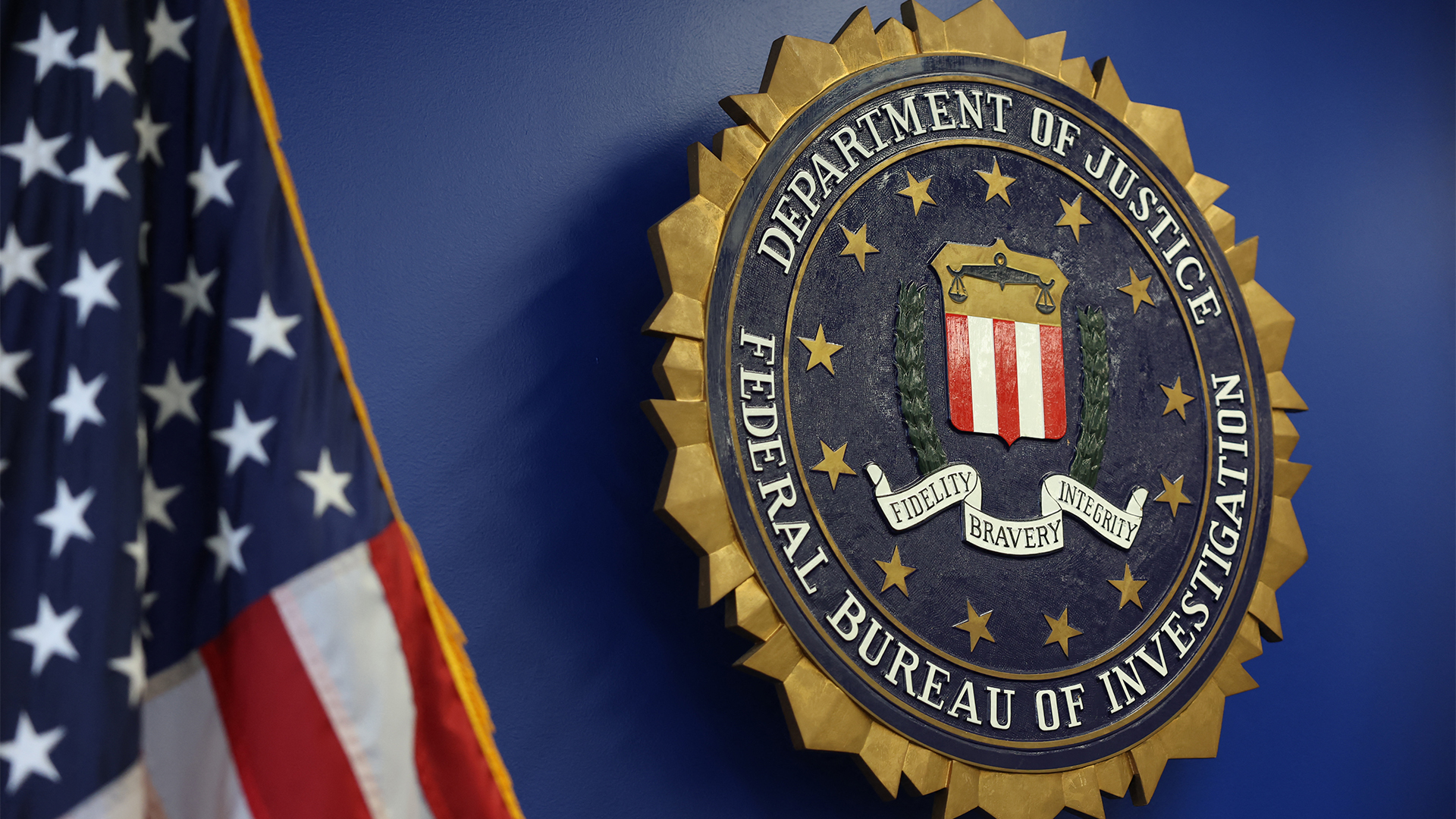 FBI logo and insignia pictured on a wall alongside a United States flag at the Los Angeles Federal Building. 