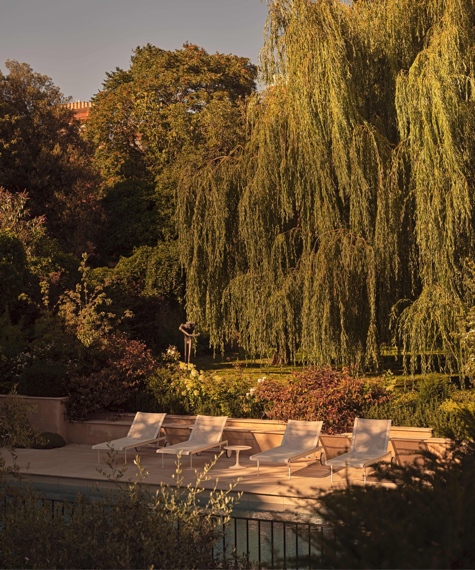 a large exterior pool area surrounded by lawn and mature trees