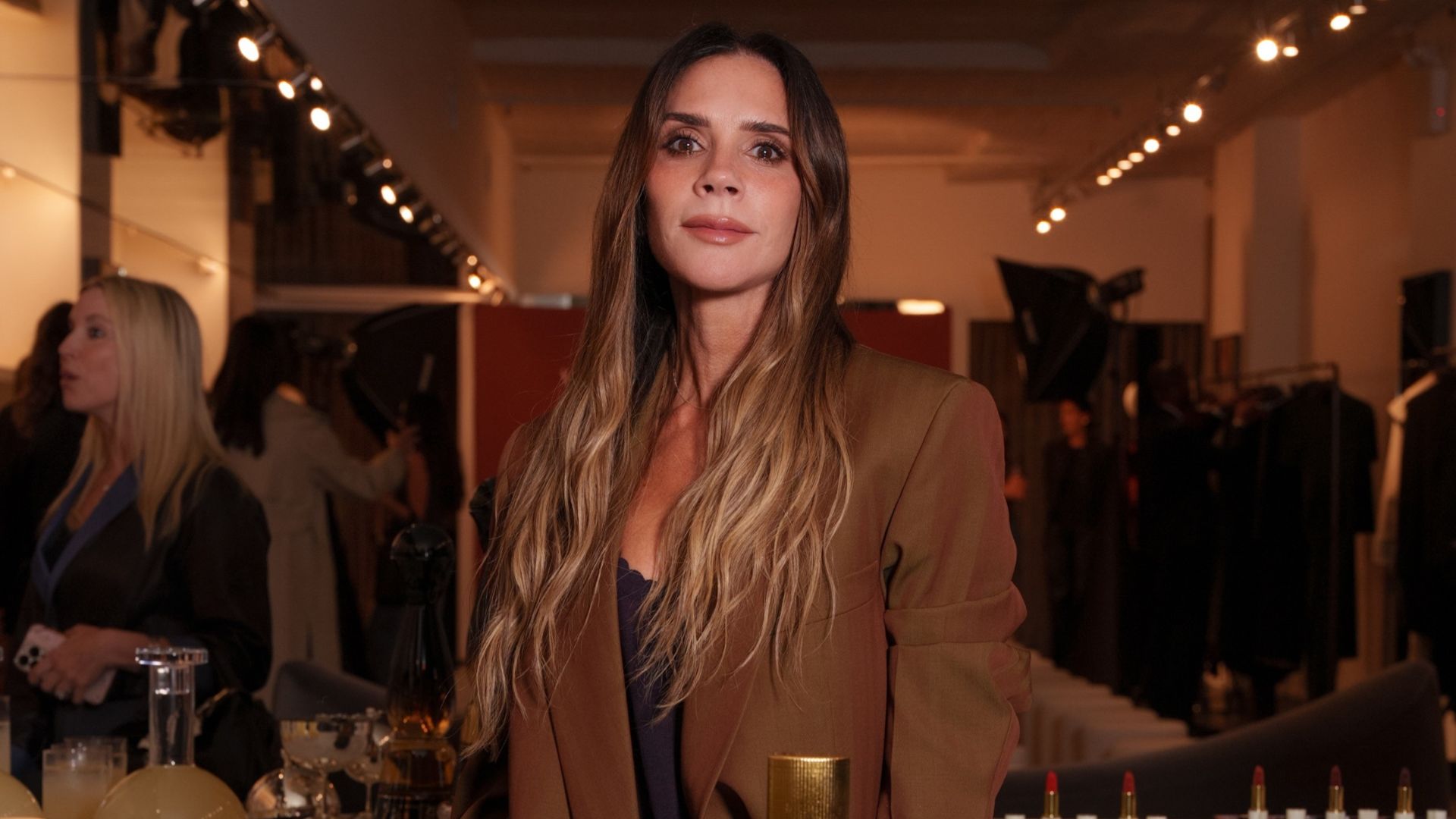 Victoria Beckham poses for a photo with Marc Jacobs wearing a brown oversized suit with a black camisole top.