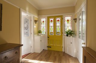 inside home with a yellow front door and stained glass windows