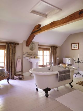 farmhouse bathroom with rolltop bath and beamed ceilling