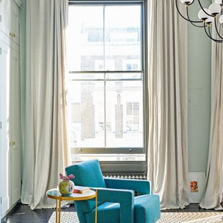Green living room with turquoise armchair and long flowing curtains