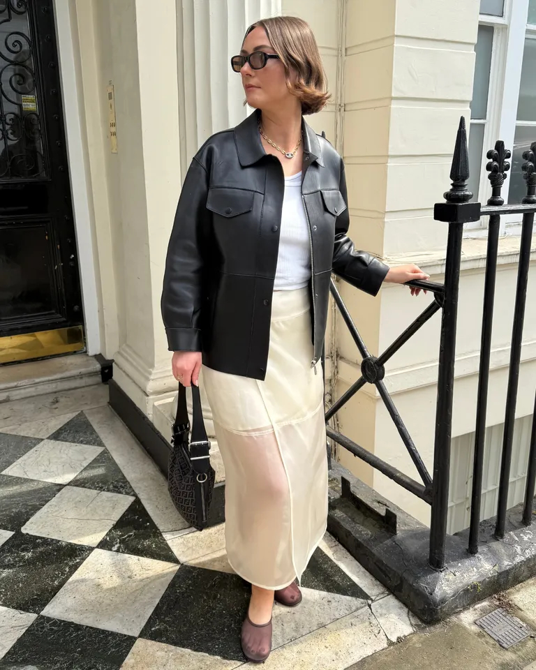 Woman wears leather jacket, white T-shirt, yellow skirt and mesh ballet flats
