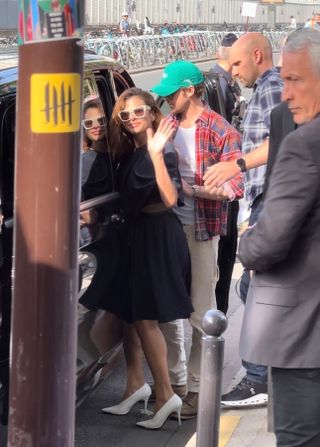 Eva Mendes wearing a navy blue knee-length dress with cream sunglasses and white pumps to the Olympics in Paris with husband Ryan Gosling.