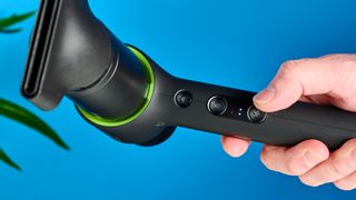 the heist 3.0 men's hair dryer in black with a bright green ring and magnetic attachment photographed against a blue background