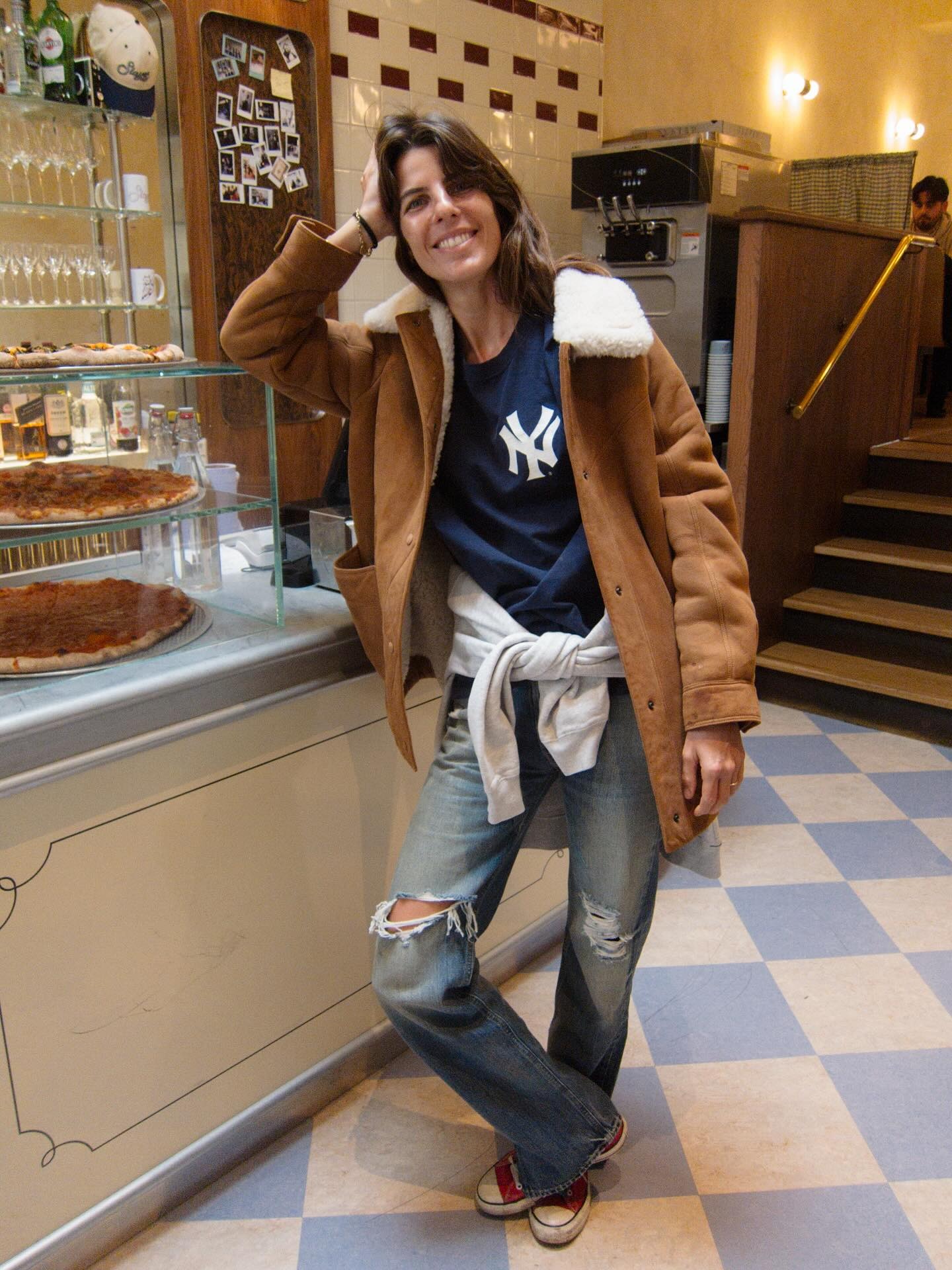 laura wears a yankees shirt, suede jacket, ripped jeans, and red converse.