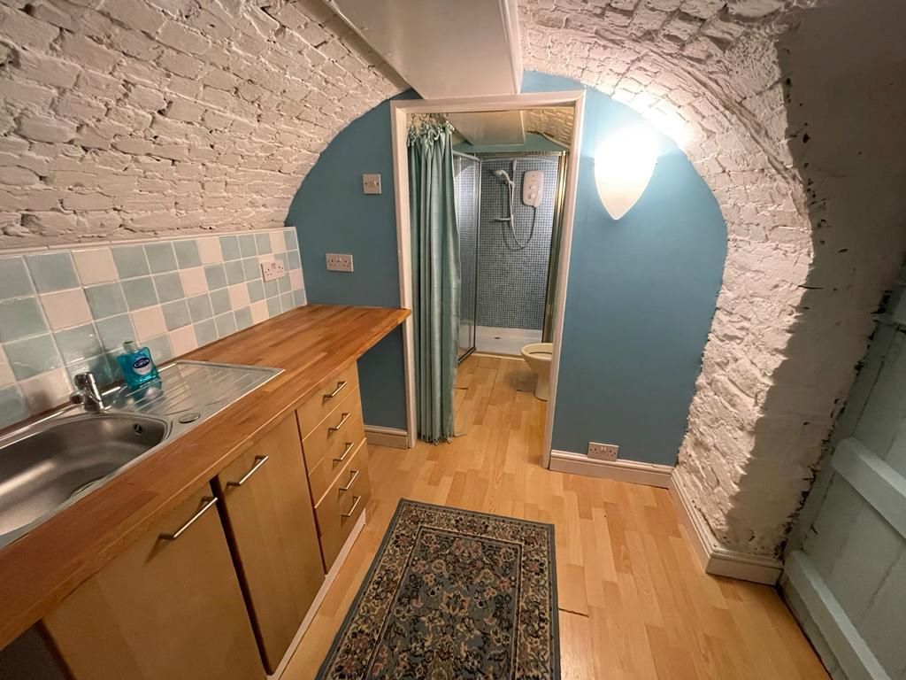 Laminate wooden floor with wooden worktop to the left of the image with metal sink