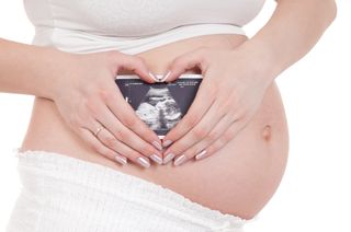 A pregnant woman holding an ultrasound photo.