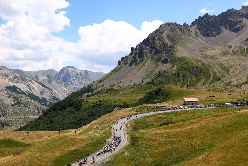 ALPE DHUEZ FRANCE JULY 14 A general view of the peloton compete beginning to climb the Col du Lautaret 2056m mountain landscape during the 109th Tour de France 2022 Stage 12 a 1651km stage from Brianon to LAlpe dHuez 1471m TDF2022 WorldTour on July 14 2022 in Alpe dHuez France Photo by Michael SteeleGetty Images
