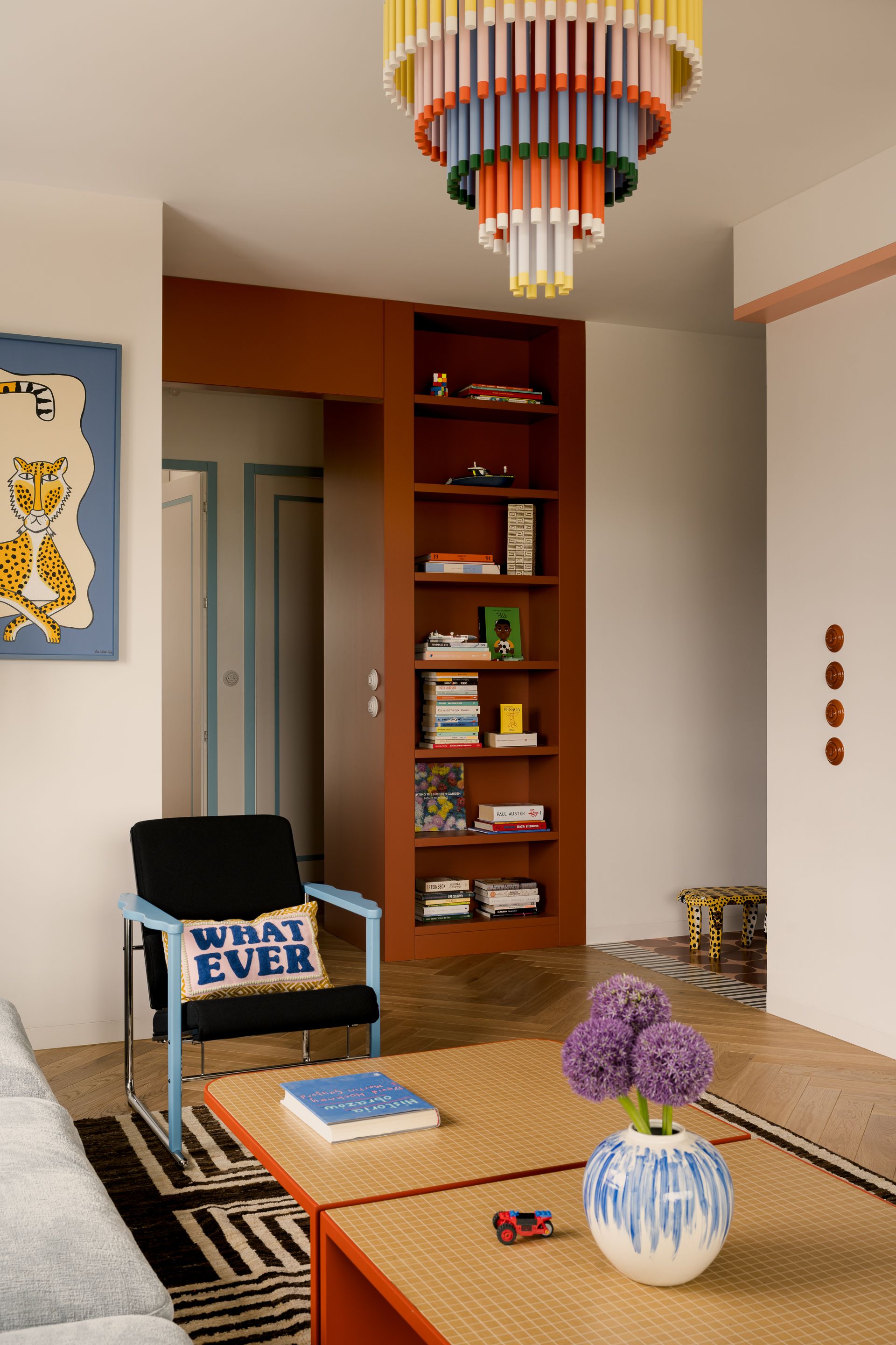 Terracotta bookshelves, a 'WHATEVER" cushion, and rainbow tiered chandelier