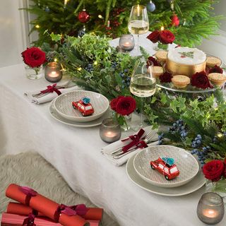 Christmas dining table with garland and roses and retro decorations on place settings