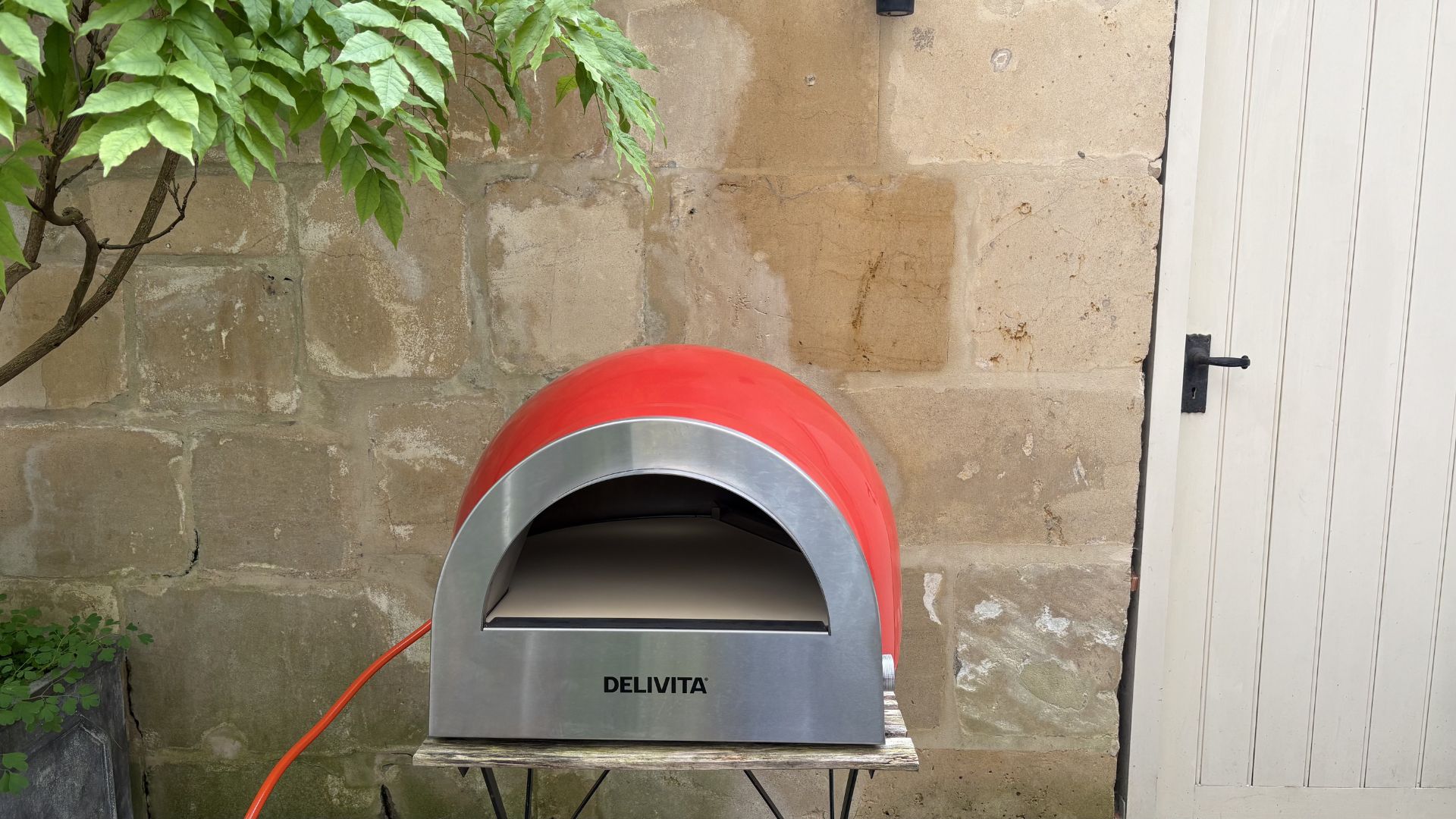 Testing the Delivita Flow Dual Fuel Pizza Oven by showing it on a table in a courtyard