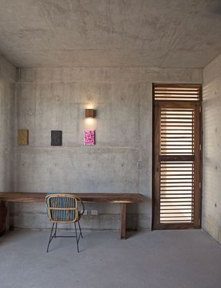 concrete room with a wooden desk, table and door with coloured panels on the wall
