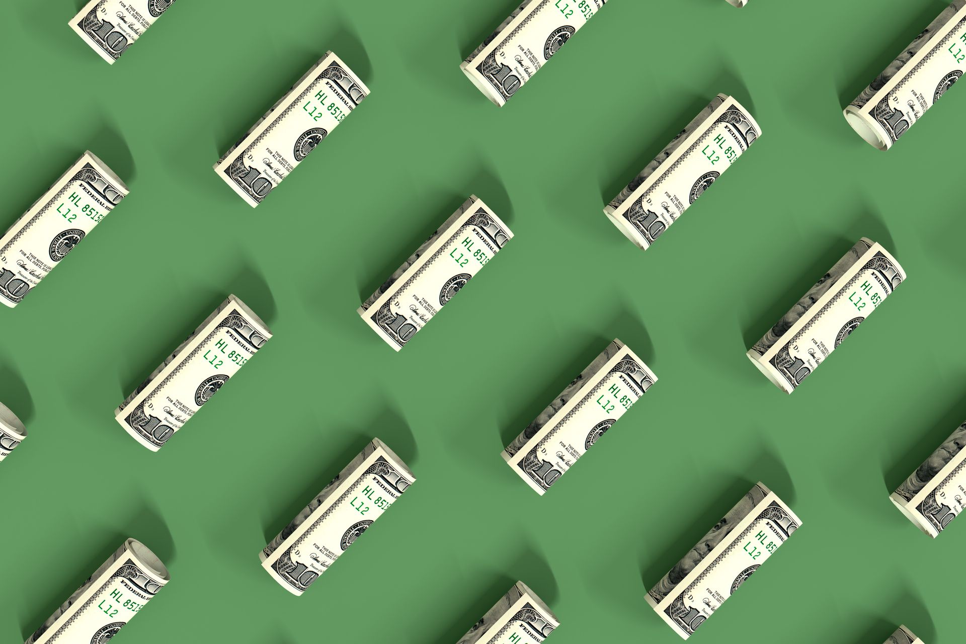 Rolled up dollar bills lie on a green surface.