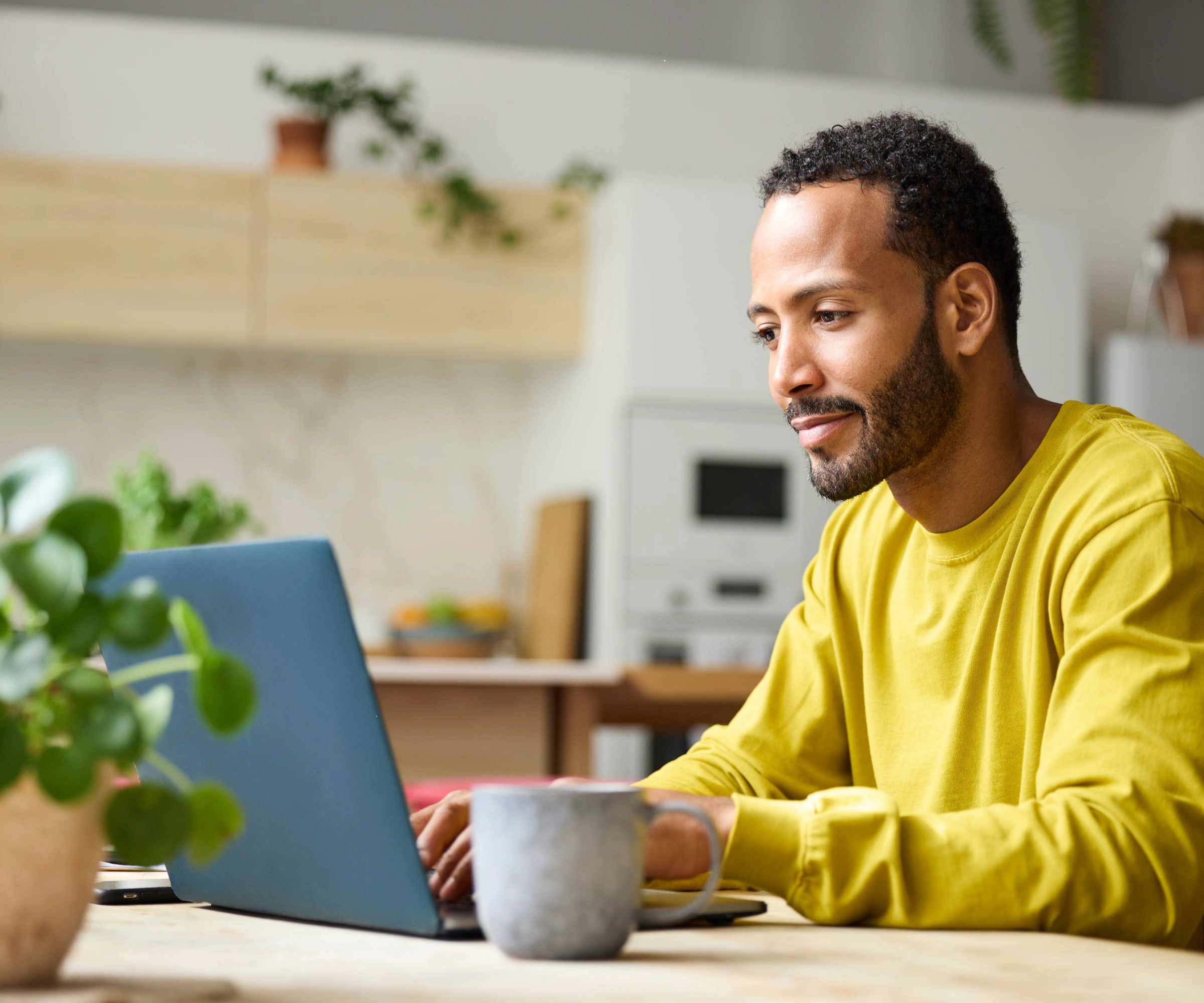 Man sitting at a laptop with a mug on the table