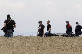 Rescuers carry bodies of passengers on a stretcher from the crash site in an area that has seen heavy fighting between separatists and Ukrainian government forces.