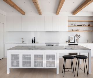 modern white kitchen with large kitchen island with dining area and black stools