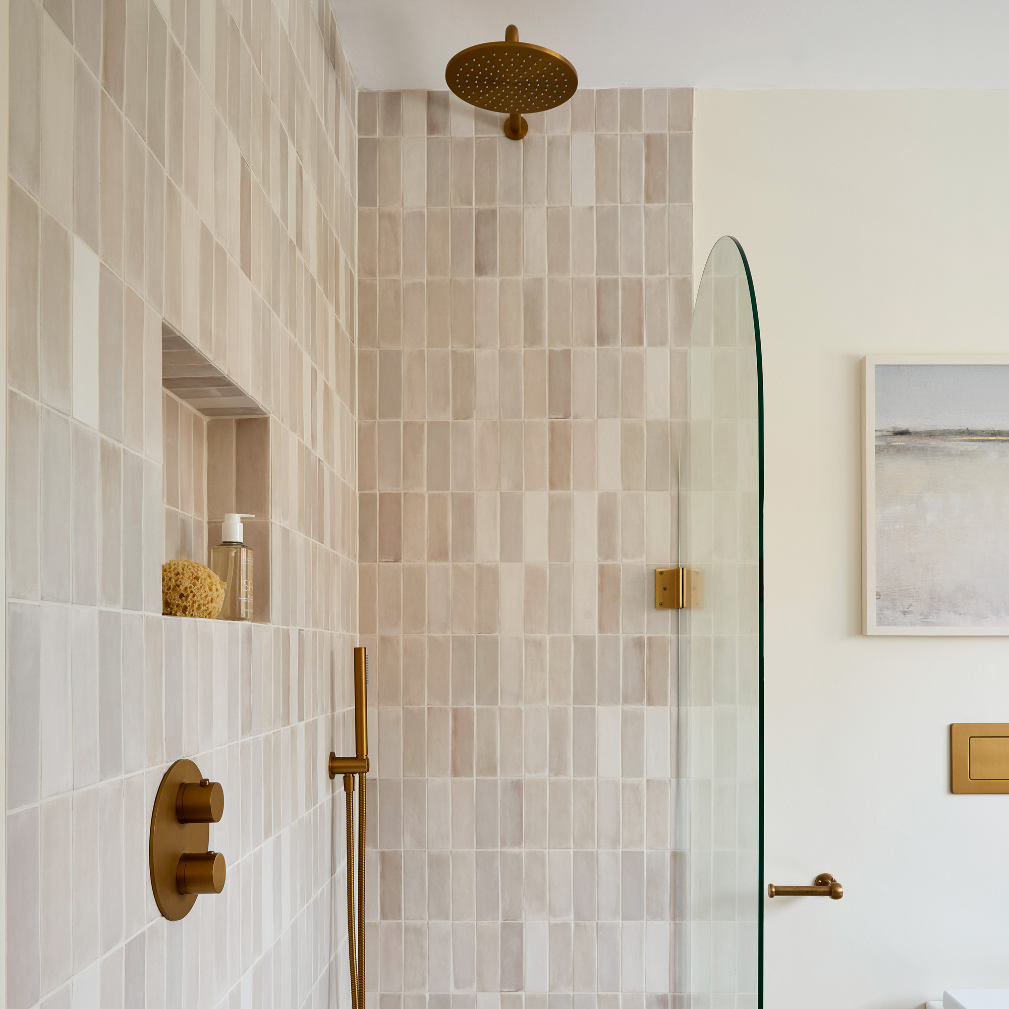 a neutral bathroom with a tiled shower area and curved glass shower screen